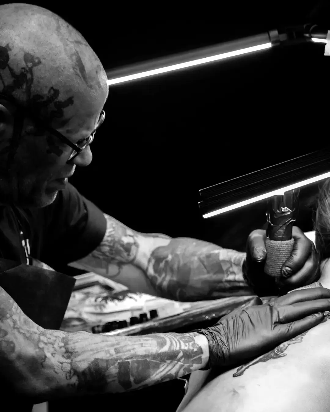 Tattoo artist working beneath studio lighting
